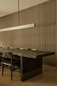 Modern minimalist restaurant interior featuring a wooden table and chairs against a wooden panel wall.