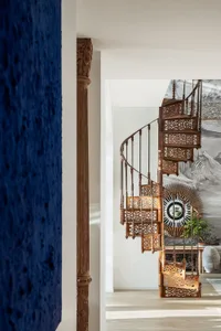 Modern, metallic spiral staircase with intricate detailing and wrought iron railings.