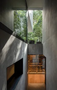 An indoor wine cellar with concrete walls, glass cabinets, and a glass-enclosed area with wine bottles.