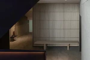 A minimalist lounge area with hardwood flooring and a wooden bench.