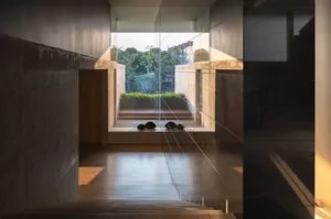 寧靜的現代客廳空間，擁有混凝土牆面與窗外綠意景觀。