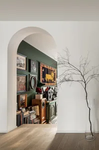 A minimalist interior with green walls, a wooden floor, and various decorative items including framed pictures and a lion rug