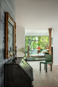 Modern living room with wooden floor, green armchair, and large windows.