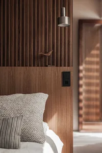 Modern, minimalist bedroom featuring a wooden headboard with a small bird sculpture on top.