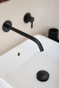 Modern black metallic faucet mounted on a white ceramic sink, showcasing sleek and minimalist design.