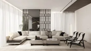 A modern, minimalist living room with white sofas, black chairs, and a wooden coffee table.