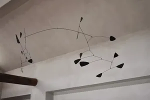 A minimalist metal abstract mobile sculpture consisting of geometric shapes arranged on a wire frame, hanging from the ceilin