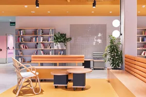 Industrial-style lobby area with concrete floor, wooden furniture, and bookshelves.