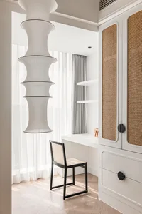 A minimalist home office with light wood cane blinds, white curtains, and white walls, featuring solid white furniture and a 