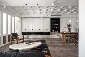 A minimalist living room with white marble accents and a black leather sofa on a black and orange leopard print rug, set agai