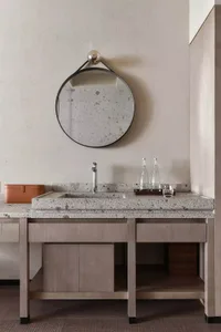 A modern bathroom with a concrete vanity including a sink, faucet, mirror, and storage underneath.