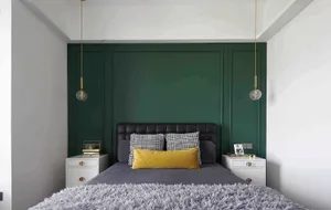 A modern bedroom featuring a green accent wall, black and white checkered pillows, and a grey bedspread.