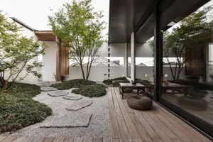Modern-style Japanese garden with wooden deck, rock pathway, and greenery.