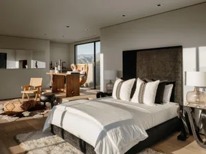 A modern minimalist bedroom with soft furnishings and a view of the mountains.
