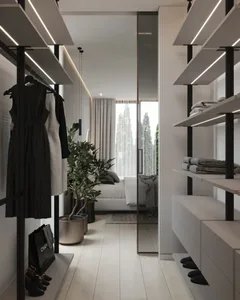 A modern plush walk-in closet with glass doors, metal shelving, and organized clothing items.