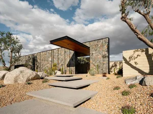 Modern residential exterior featuring stone cladding and concrete materials.