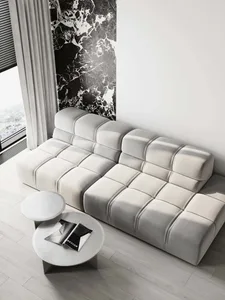 White modular sofa with tufted cushions in a modern living room featuring marble accents.