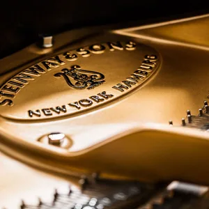Close-up of a metallic, branded golden keyboard for a Steinway piano.