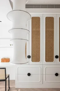 Modern white closet with rattan trim and black knobs.