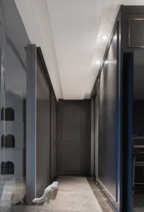 A modern interior corridor with metallic wall panels and a white cat walking on the floor.
