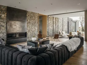 A modern living room with stone walls, a fireplace, and plush seating.