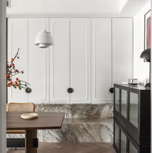 A modern kitchen with white cabinets, marble backsplash, and a wooden dining table.