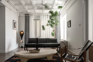 A contemporary living room featuring a black leather sofa and an oval-shaped coffee table with a textured surface.