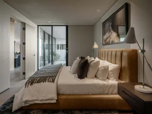 Modern minimalist bedroom featuring a fabric upholstered bed with a sleek, upholstered headboard and a side table with a floo