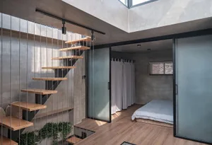 A modern minimalist bedroom with wooden stairs, metal railings, and glass walls.
