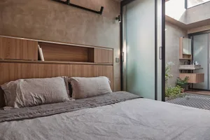 A modern minimalist bedroom with wooden furniture and a concrete wall