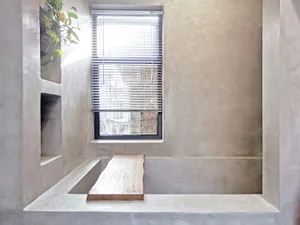 Window with blinds in a modern minimalist bathroom made of concrete.