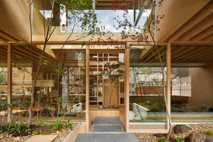 A minimalist residential courtyard featuring glass walls, wooden flooring, and concrete elements.
