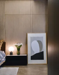 A modern bedroom featuring a wooden textured wall and a bedside table with a spherical lamp and a vase with white flowers.