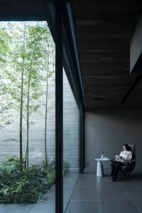 A modern interior space with concrete walls and glass window showcasing a serene garden view.