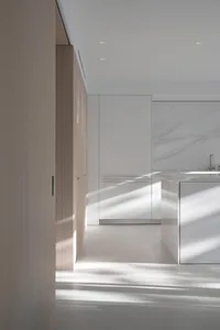 A sleek, modern kitchen with white marble countertops and wooden cabinets.