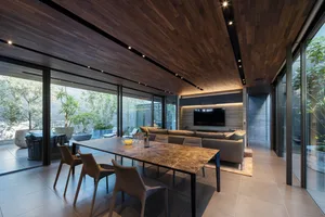 Modern living and dining room with wooden ceiling, glass walls, and marble table.