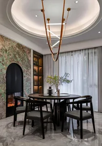 Modern minimalist dining room with granite floor, circular table, black chairs, and contemporary lighting.