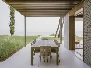 Outdoor dining area featuring a wooden table and rattan chairs with a sea view.