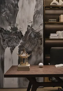 A modern office desk with a wooden top and a minimalist design sits in front of a mural depicting a mountain landscape. The d