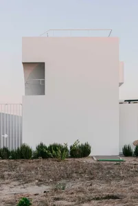 Modern residential building with a curved, concrete exterior and a rooftop balcony.
