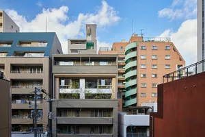 A modern residential building with brick and concrete exteriors, featuring balconies and urban infrastructure.