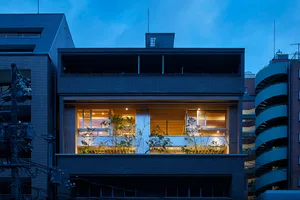 Modern residential building exterior with brick facade and illuminated windows.