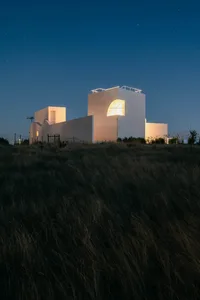 A minimalist building with a concrete exterior at night.