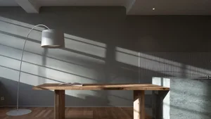 A minimalist wooden desk with a sleek, modern floor lamp casting long shadows on a gray wall.