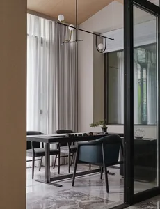 Modern minimalist dining room featuring leather and metal furniture, glass window, and contemporary lighting.