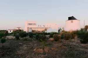 A minimalist house with white exterior walls and a glass facade.