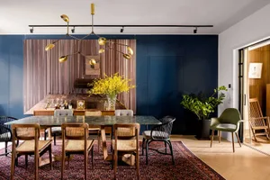 Modern dining room with marble table, wooden chairs, and metal lighting fixture.