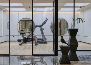 Modern industrial home gym with wooden floors and minimalist decor.