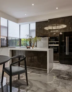 Contemporary kitchen featuring modern marble countertops and stainless steel appliances, with a black chair in the foreground