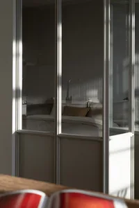A modern minimalist bedroom with white walls and a bed adorned with white bedding and a brown pillow.